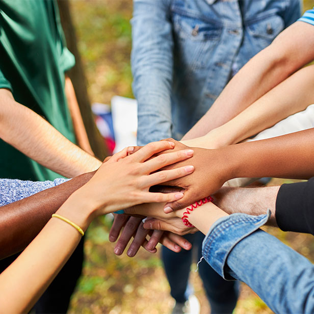 mixed race international group of young people gathered outdoors, they holds hands together. friendship concept.