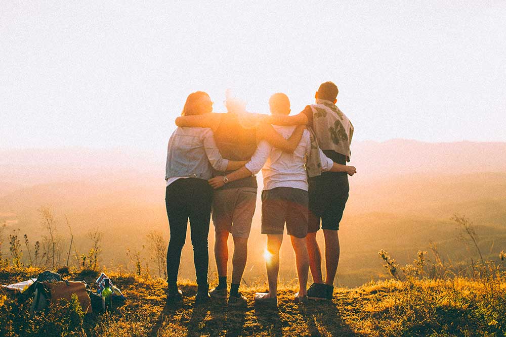 group of friends hugging watching the sunset