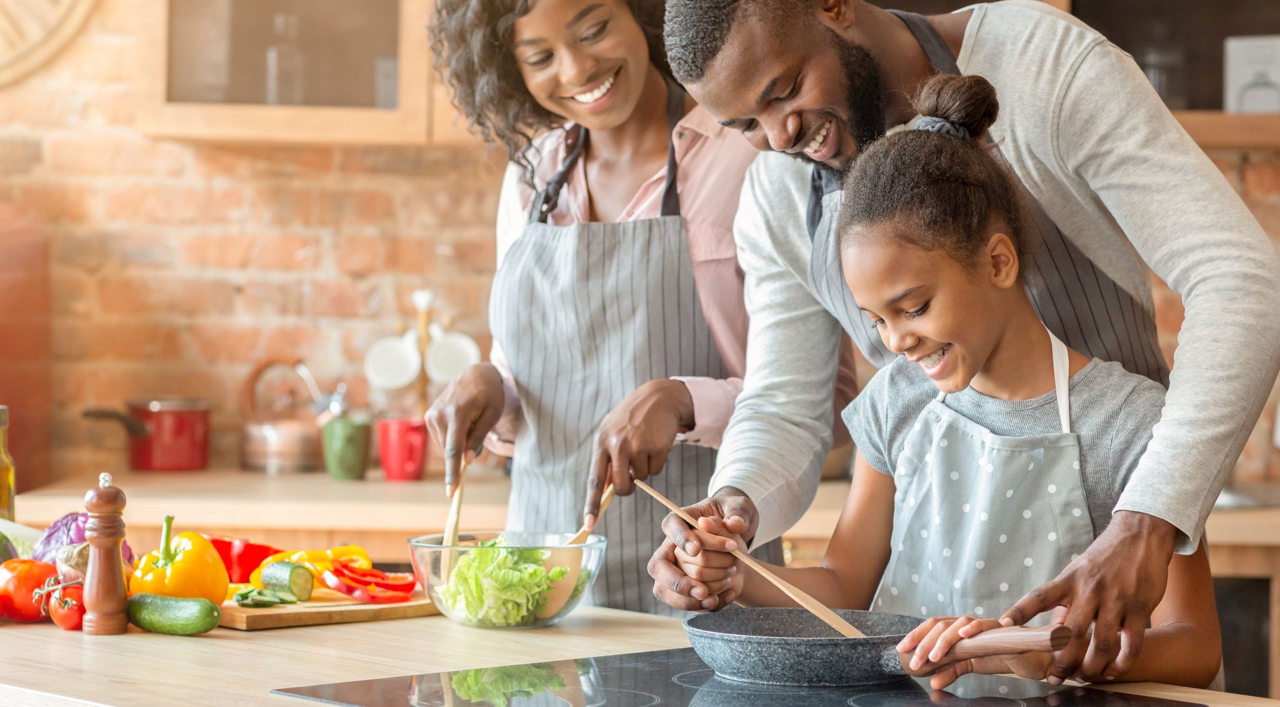 Family of three preparing dinner over an induction stove