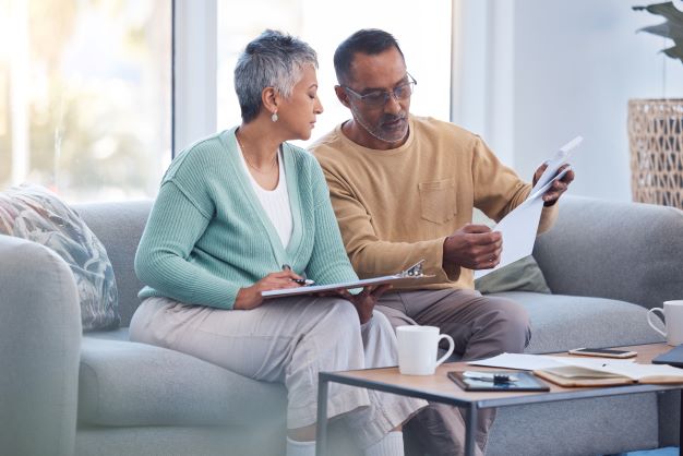 Couple sitting at home on their couch reviewing paperwork together