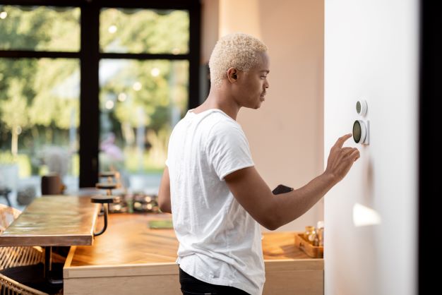 Person in their kitchen interacting with a smart thermostat