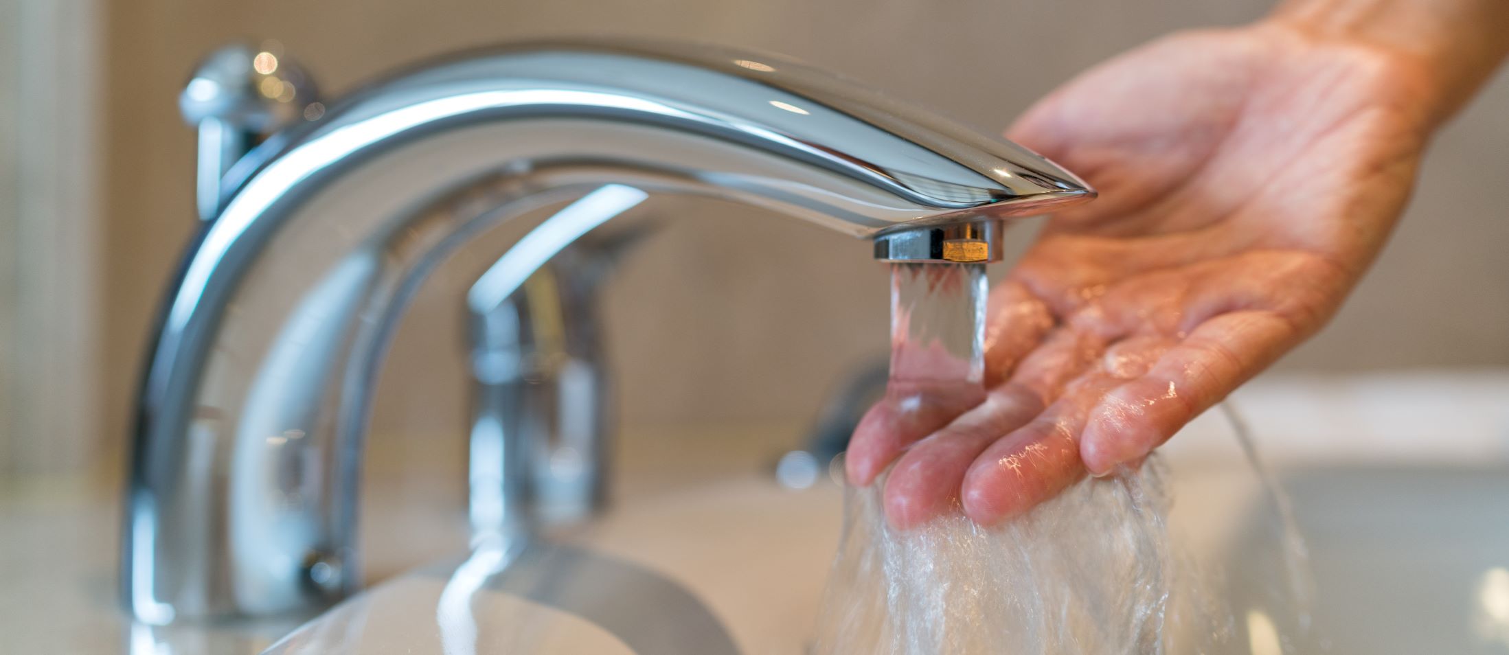 hand testing the temperature of water coming out of a faucet