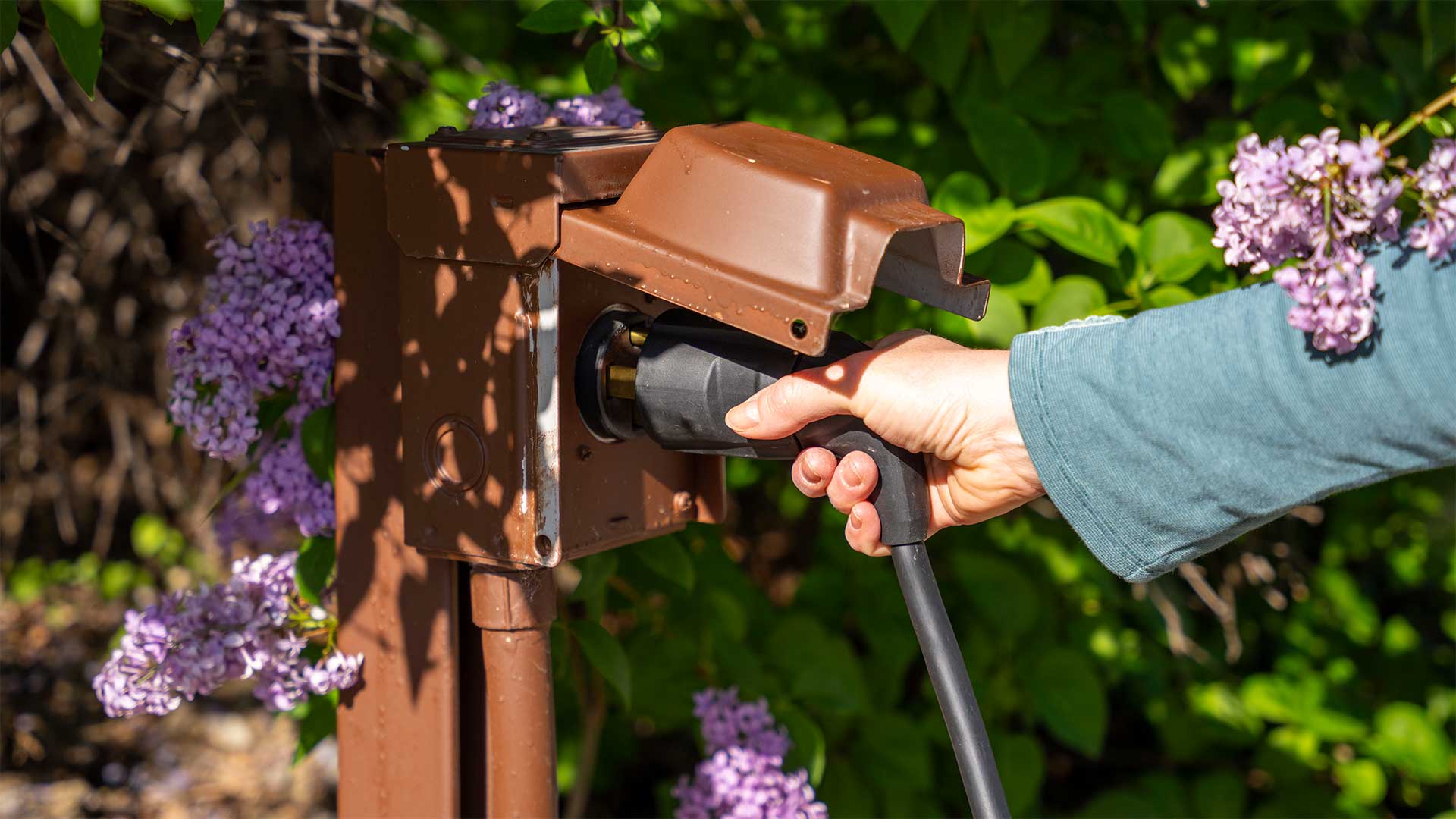 A person inserting a plug into a level 2 charger.