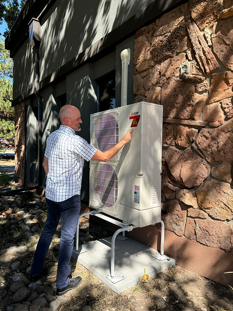 A man points to his commercial heat pump outside of a building.