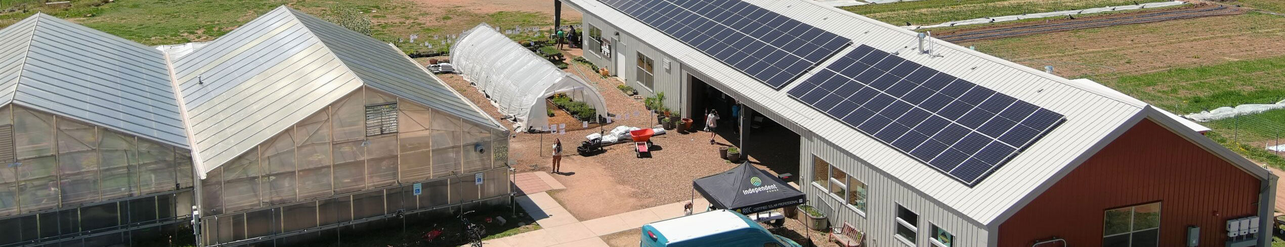 Building-Electrification-Header A large barn with solar panels on the roof is next to two greenhouses