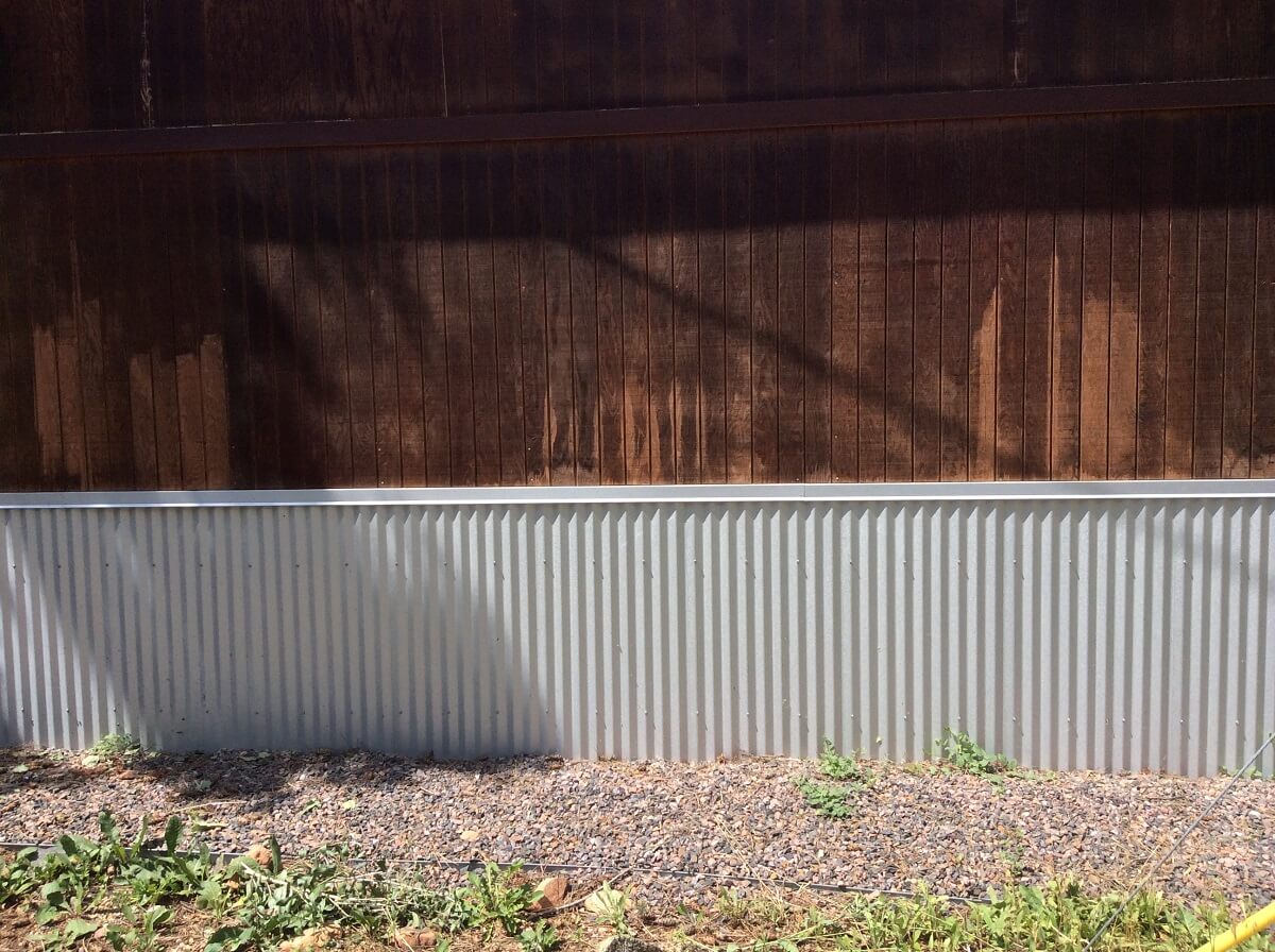 Corrugated metal installed at base of wooden home exterior