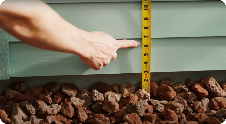 Measuring tape along the outside of a house measuring 6 inches