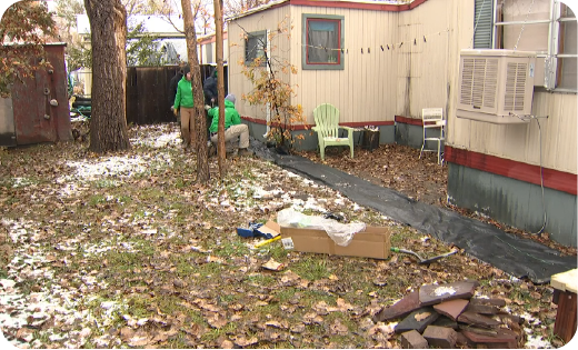 Team of workers building rock barrier around mobile home