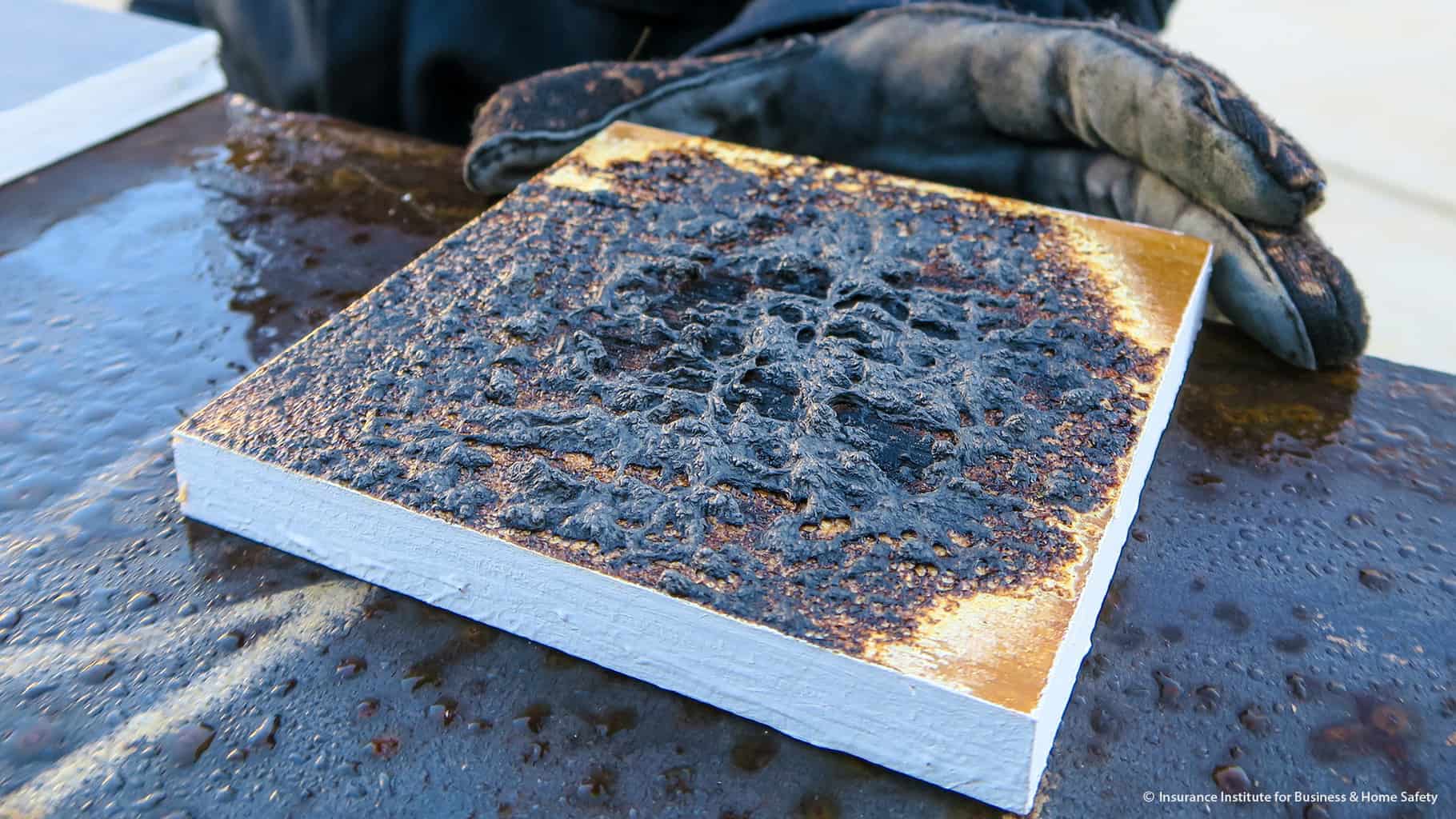 Fresh fire-retardant coating testing with a charred slab of material, showing ineffectiveness