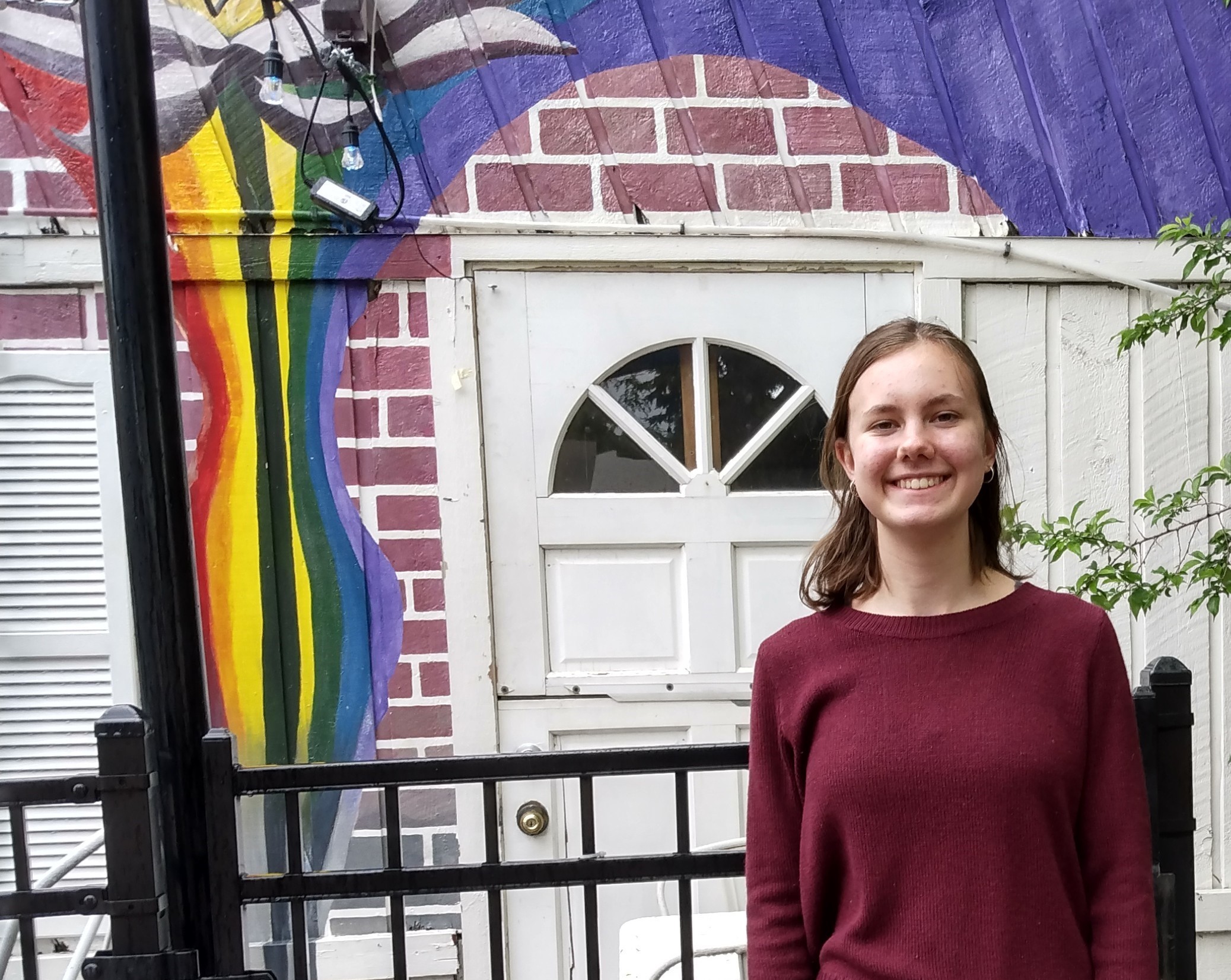 Morgan Kirk standing in front of door with mural around it