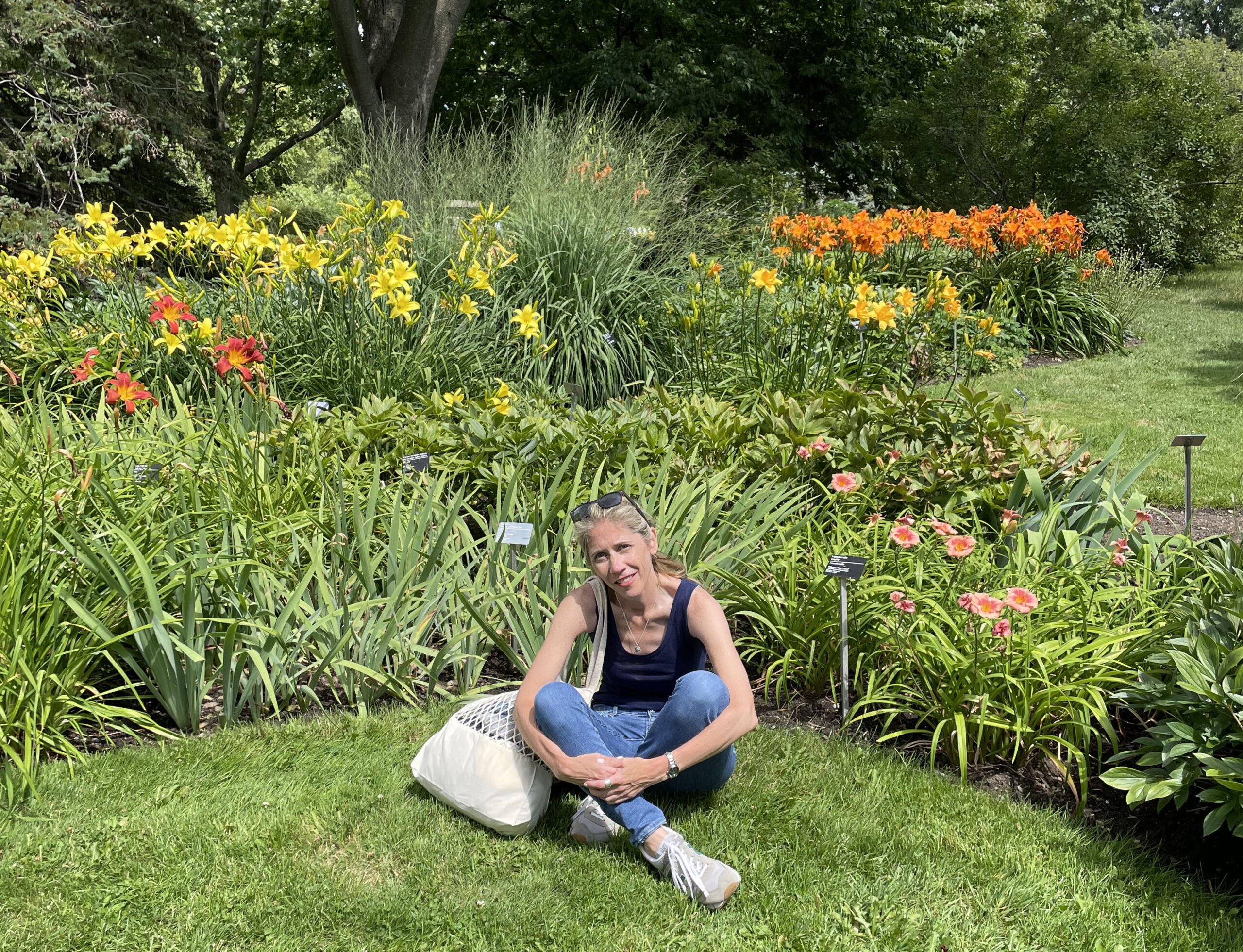 Elaina Verveer sitting in grass in front of flowers